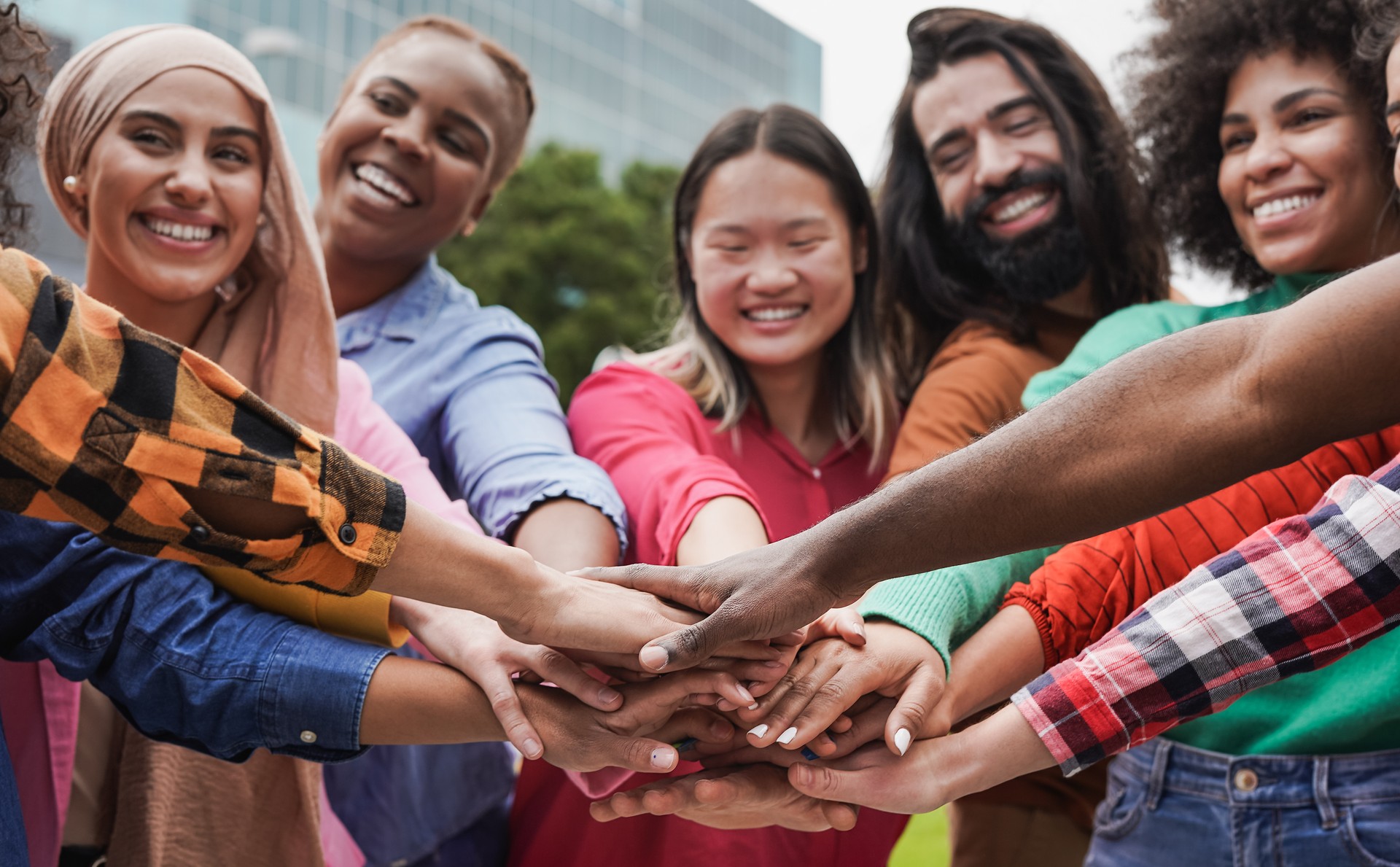 Group of young multiracial people stacking hand in the city